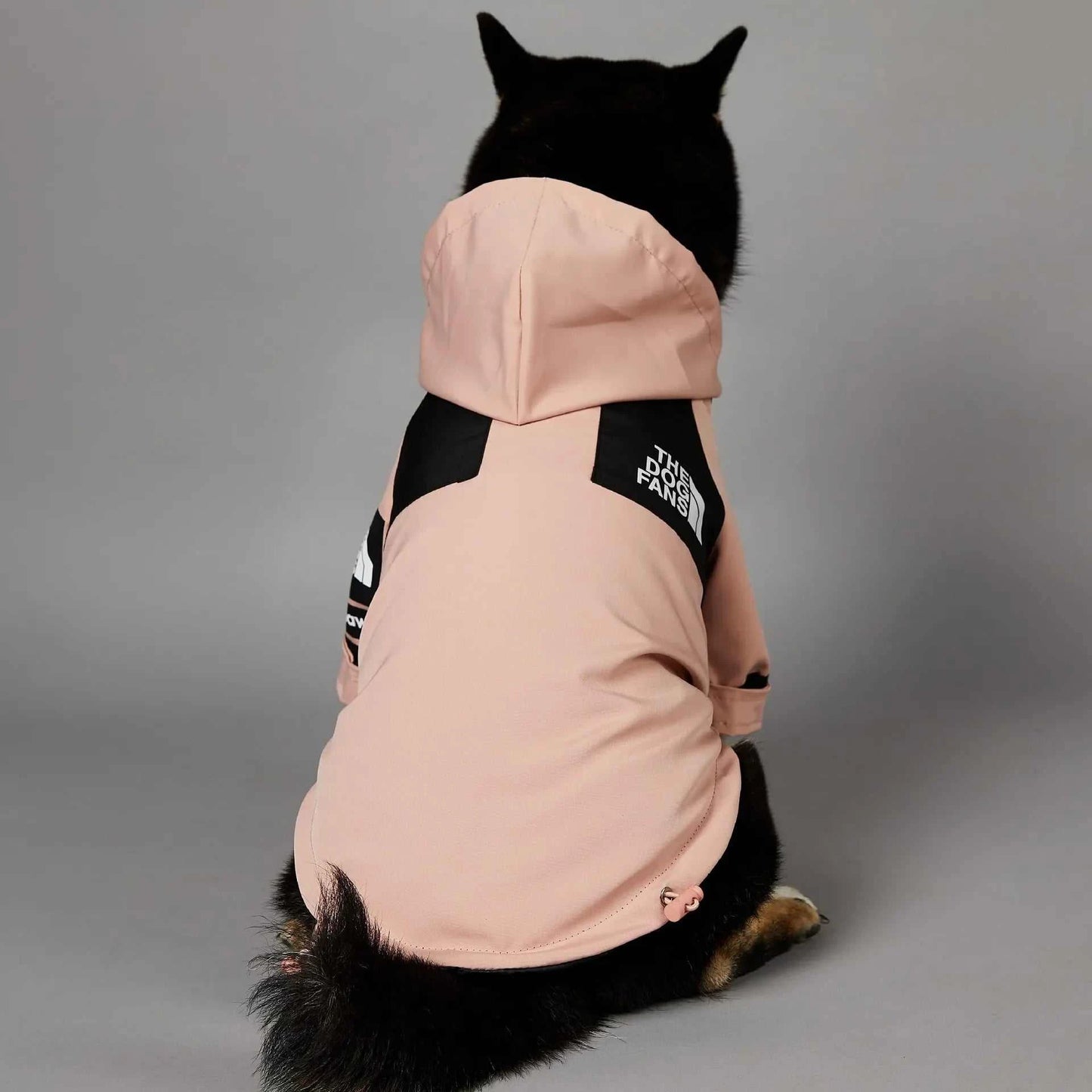 Pink rain jacket for dogs featuring a hood and black accents for stylish weather protection.