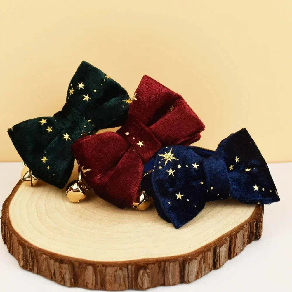 Set of three personalised cat collars with soft adjustable velvet bows in green, red, and navy, decorated with gold star patterns and small bells