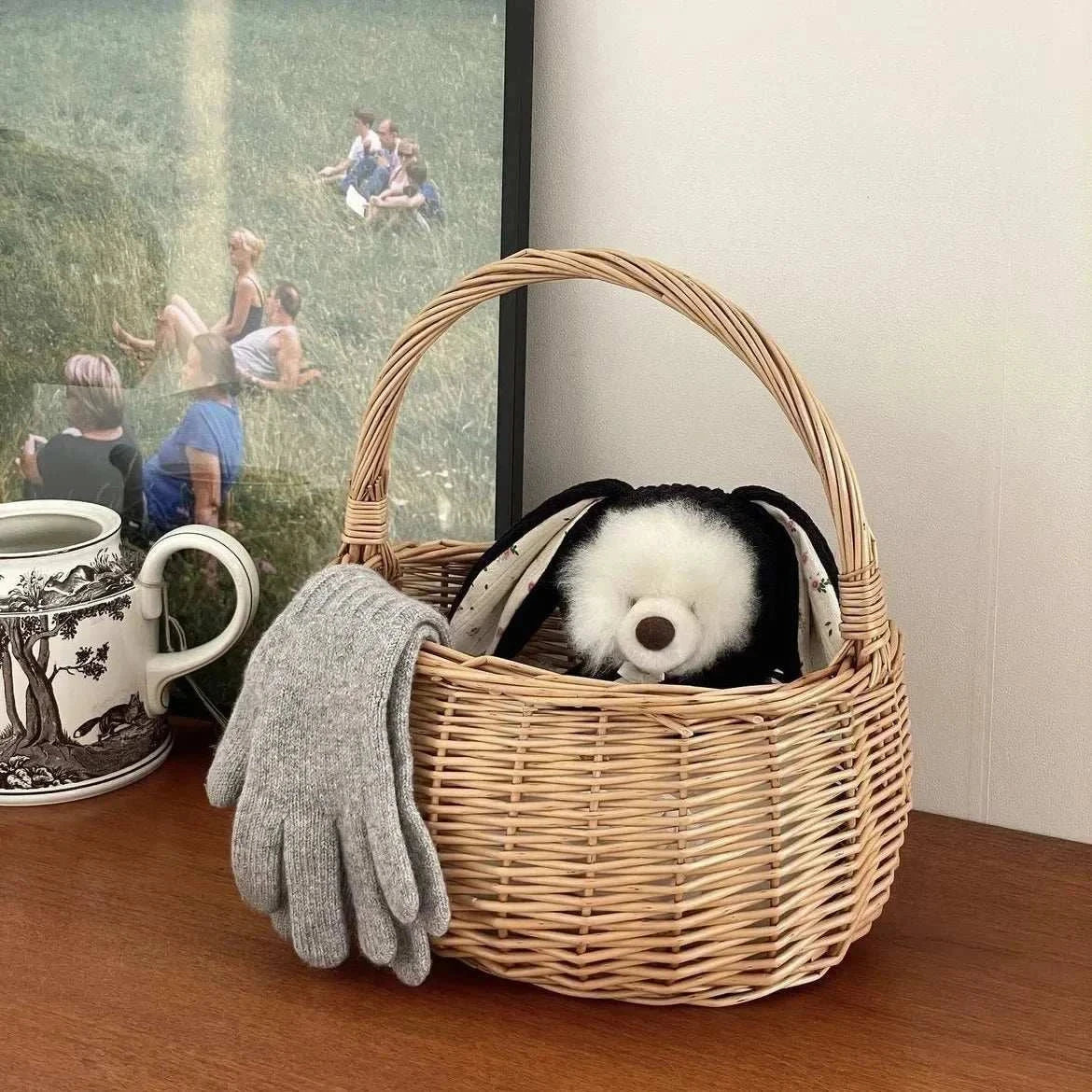 cute knitted rabbit ears dog hat in wicker basket with gray gloves and black white plush toy inside