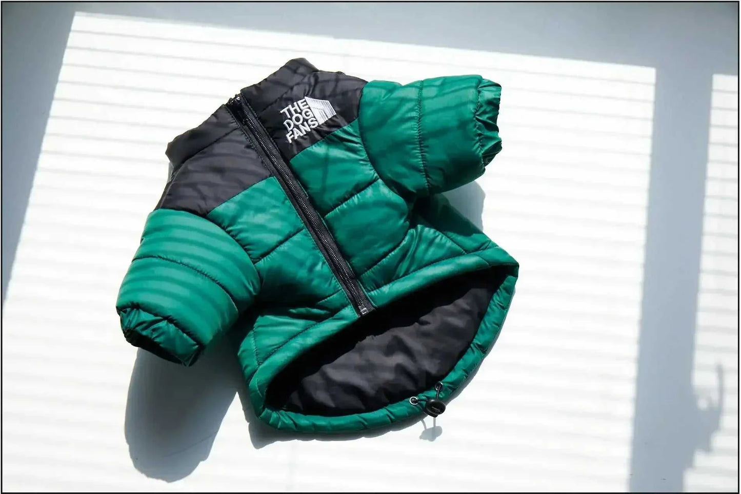 Green and black winter down puffer jacket for dogs with zipper closure.