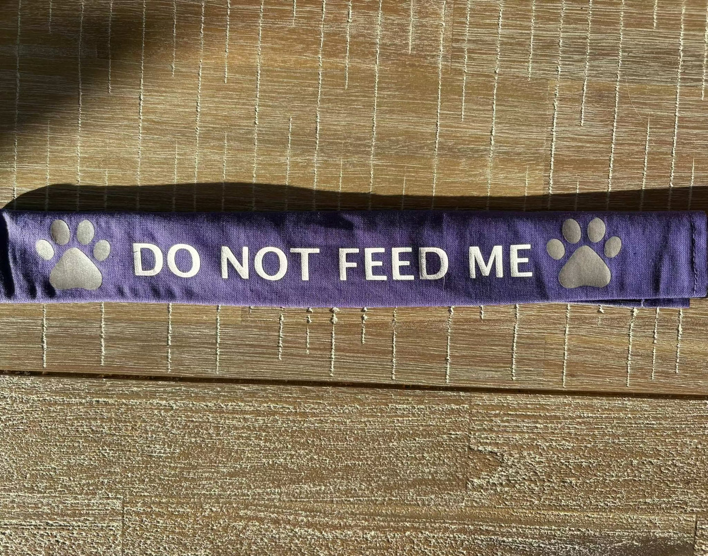 Purple cotton lead slip for dogs with "DO NOT FEED ME" text and paw prints, designed for safety and communication.