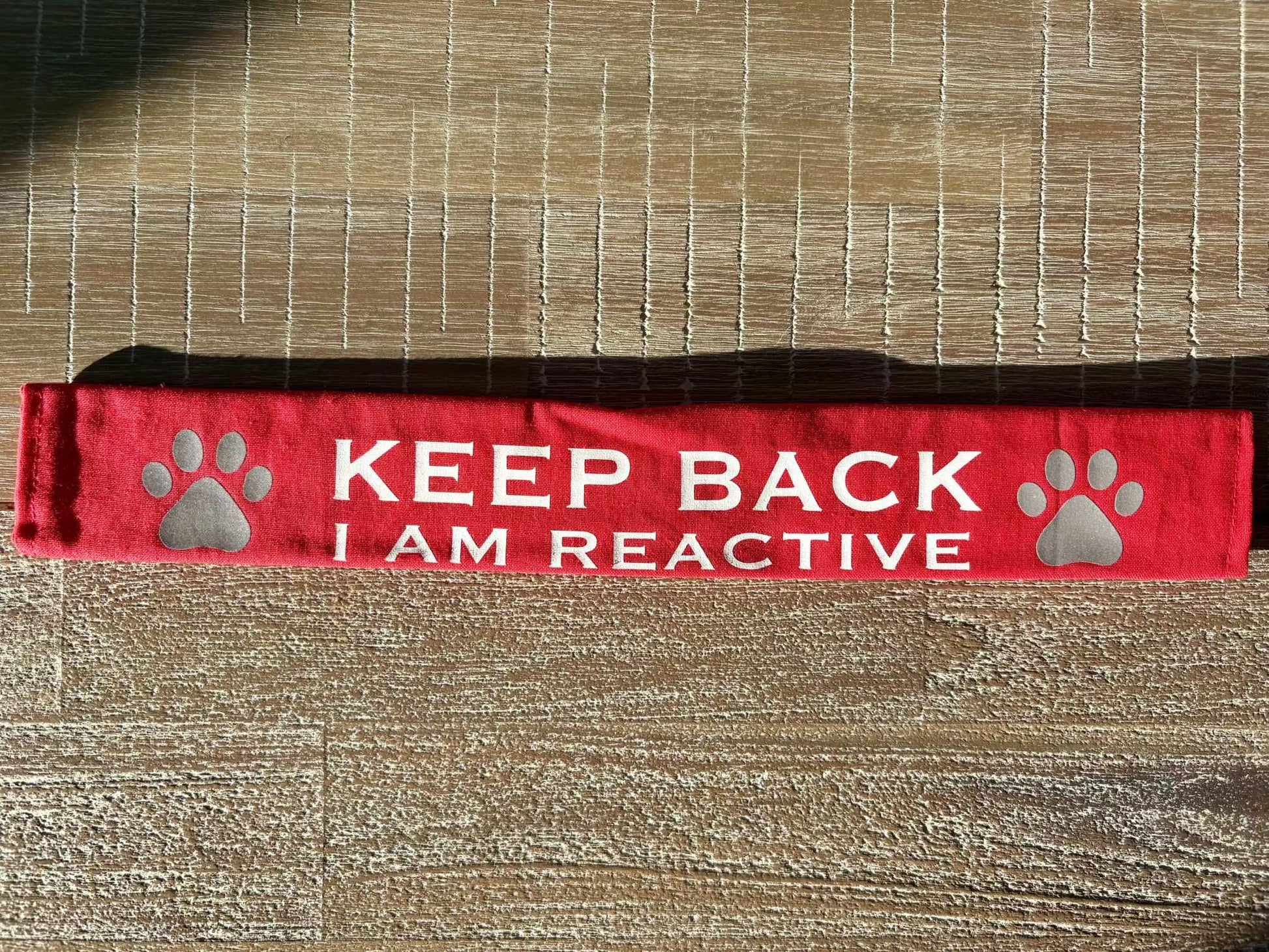 Red lead slip for dogs with reflective paw prints and "KEEP BACK I AM REACTIVE" text for safety and communication.