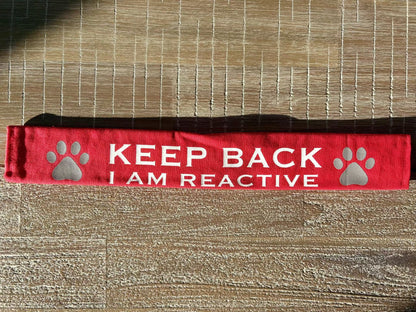 Red lead slip for dogs with reflective paw prints and "KEEP BACK I AM REACTIVE" text for safety and communication.