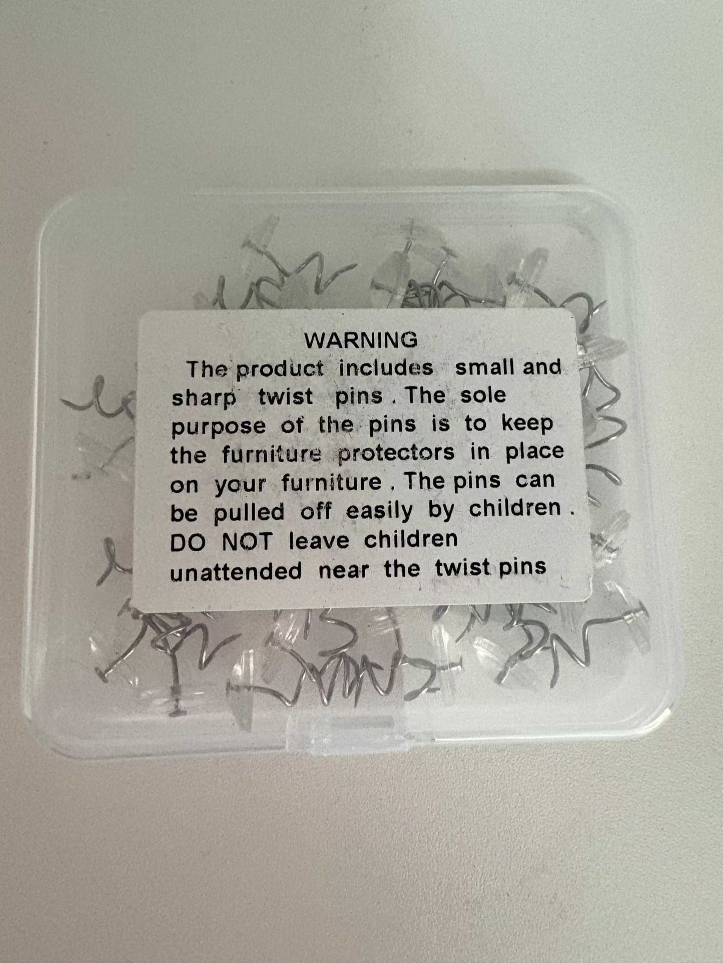 Clear plastic box of twist pins for Cat Scratch Deterrent Tape furniture protection with safety warning label