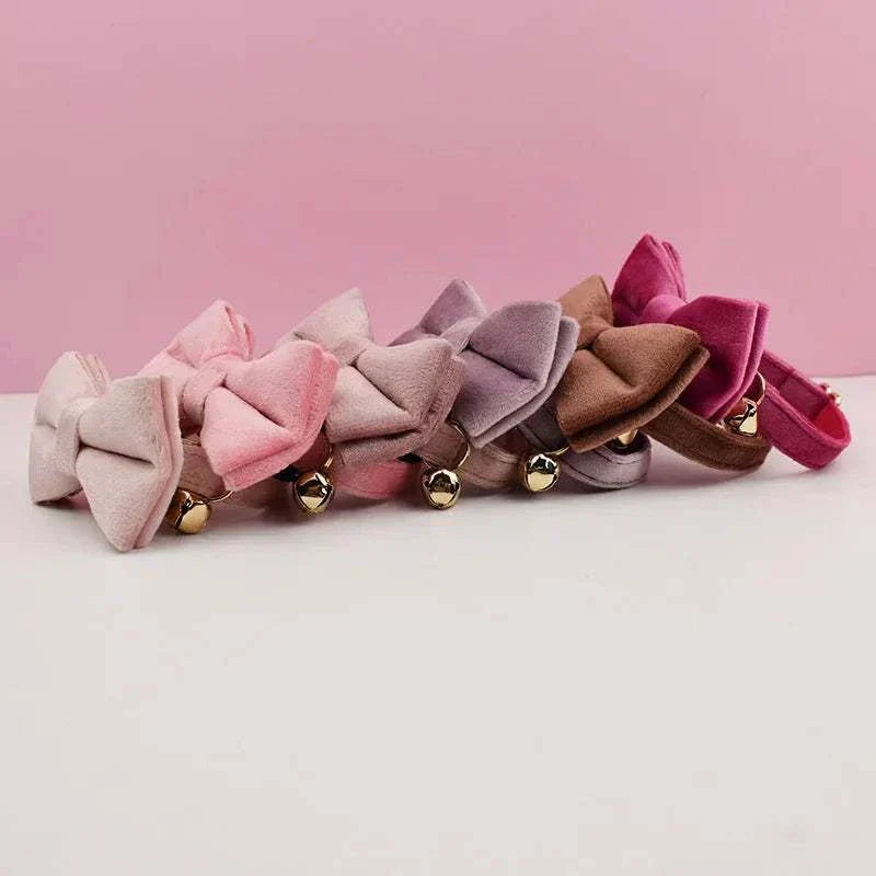Luxury velvet cat collars with bow ties and bells in various pastel colors on pink background