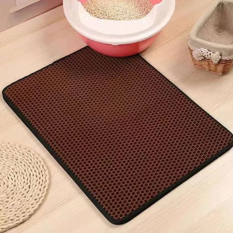 Cat litter mat with double layer honeycomb design, waterproof and urine proof, on wooden floor near litter box.