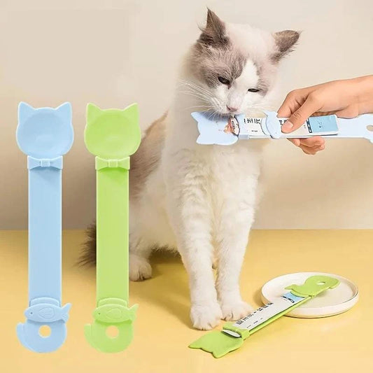Cat Strip Spoon Feeder in blue and green with cat-shaped handle feeding a white fluffy cat safely and cleanly